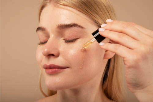 une femme qui s'applique de l'huile sur le visage avec une pipette