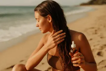une femme qui s'applique de l'huile végétale sur les cheveux à la plage
